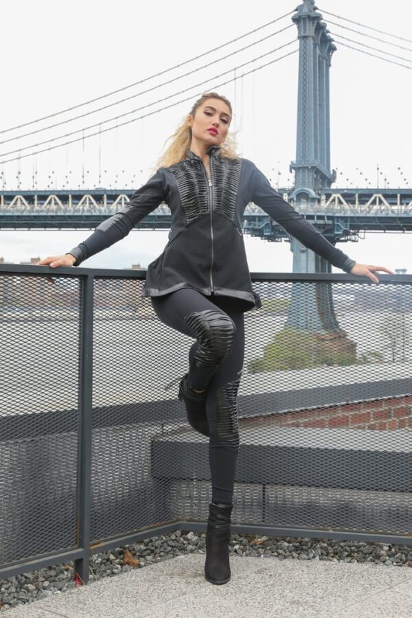 Model posing in stylish black outfit outdoors.