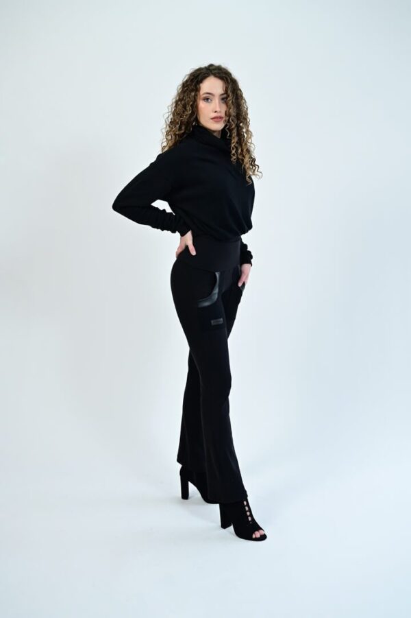 Woman in black outfit with curly hair.