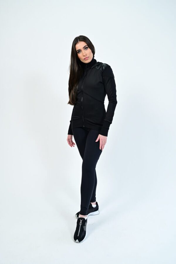 Woman in sporty black outfit posing confidently.