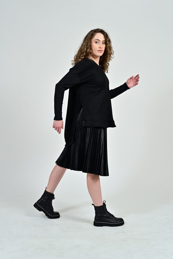 Woman in black outfit with pleated skirt.