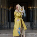 Woman in yellow coat holding small dog.