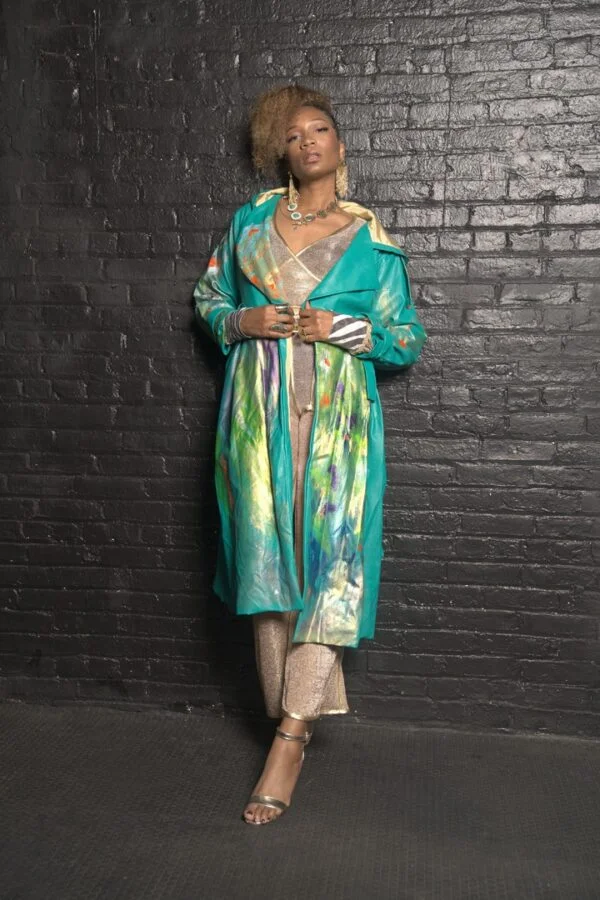 Woman in teal art coat and gold pants.