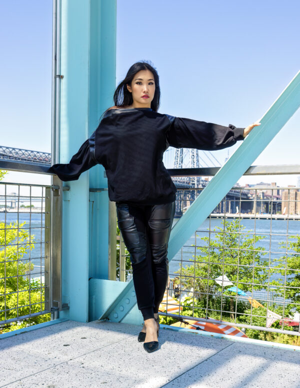 Woman in black outfit near water.