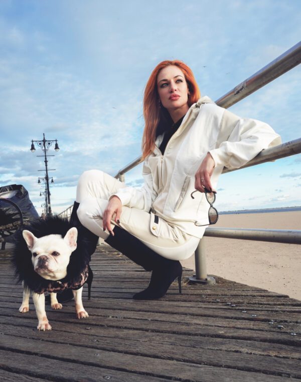 Woman in white outfit poses with dog.