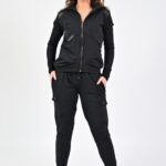 Woman in black tracksuit standing confidently.