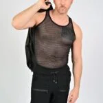 Man in mesh shirt holding jacket.