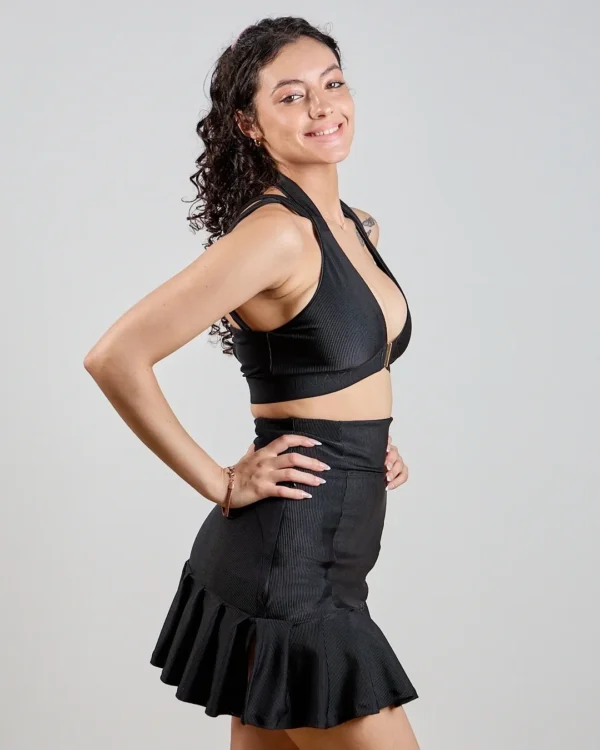 Woman in black outfit smiling confidently.