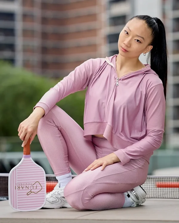 Woman in pink sportswear holding paddle.