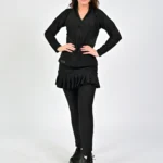 Woman in black outfit standing confidently.