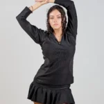 Woman posing in black dress, arms raised.