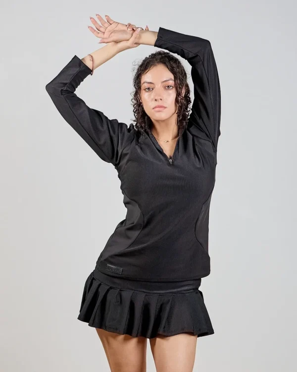 Woman posing in black dress, arms raised.